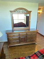 Full front view of the double dresser with mirror showing hardware, drawers, cabinet door, and bun feet.