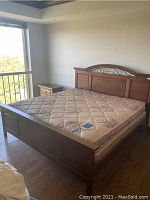 Full view of king bed frame with mattress showing wood panel footboard, ironwork, and floral mattress.