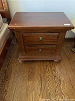 Top down view of the nightstand showing two drawers and medium brown wood finish with some wear marks on top surface.