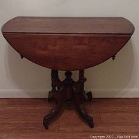 Closed drop leaf table showing the half moon shape with wings folded down and turned legs with casters