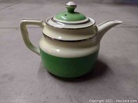 Front view of ceramic coffee pot in white and green with silver trim, lid on