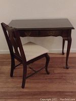 Desk and chair set shown together, desk has glass top and wooden drawers, chair has cream-colored fabric seat.