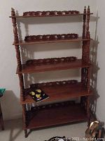 Front view of the antique wooden 5-shelf bookcase showing turned spindles and carved latticework.