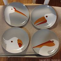 Front view of all four different bird portrait plates by Fitz and Floyd showing distinct bird beak designs and colors on gray background.