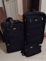 Photo of entire three-piece black luggage set on carpeted floor.