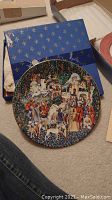 Front view of the medieval-themed 'La Chasse à la Licorne' decorative plate with detailed colorful imagery and a blue box with gold fleur-de-lis pattern in the background.