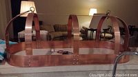 Copper hanging rack made of copper bands with rivets and hooks for hanging pots and pans.