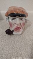 Front view of the Sherlock Holmes head-shaped ceramic jar with pipe and hat lid in place.