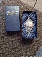 Box for Thomas Kinkade Crystal Ornament with gold lettering on black lid along with ornament inside box on black satin lining.