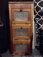 Front view of the closed wooden potato and onion storage bin showing three drawers with metal mesh panels and round metal knobs.