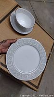 Photo showing plate and bowl with light grey floral scroll border on white porcelain.