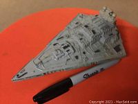 Top angle view of the diecast Star Destroyer model alongside a Sharpie marker for scale, showing detailed molded surface and paint wear