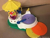 Side and top view of the Fisher Price vintage carousel turntable toy showing colorful carousel seats and record player with records.