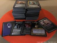 Large stack of Star Trek gaming cards on a round orange table with some individual cards spread in front showing characters, events, and game elements