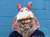 Mask worn on head showing front facial features and eye stalks.