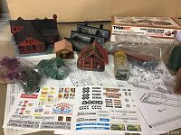 Lot overview showing model buildings, decals, foliage bags, and Tyco kit box