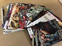 Overview of assortment of 22 Wolverine Origins comics fanned out showing painted covers with Wolverine images and other characters