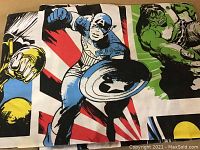 Close-up photo of the sheet showing Captain America and Hulk in vibrant comic style graphics with bold red, green and blue background elements.