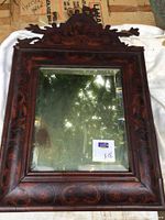Full view of antique mirror showing the ornate carved crest and floral marquetry inlay on wooden frame.