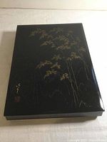 Top-down view of the black lacquer box showing gold bamboo artwork and artist signature with red seal.
