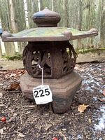 Side front view of the iron garden lantern showing the ornate cut-out design and weathered surface with moss and rust.