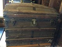 Front view of the domed trunk showing overall condition, wood slats, metal reinforcements, and wear.