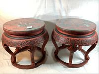 Two red lacquered round side tables or stools with glass tops side by side