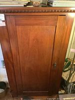 Front view of large wooden cabinet showing single door and key lock.