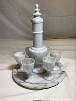 Full view of sake set with decanter, c stopper, six cups, and round tray on white backdrop