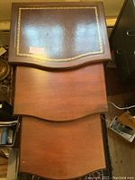 Top view of the three nesting tables stacked, showing the largest table's leather top with a gold painted stenciled border.