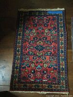 Full view of small oriental throw rug showing overall pattern and colors on wooden floor