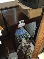 Full view of the wooden side table showing the pie crust edge top, one lower shelf, and overall shape with some items stored on it.