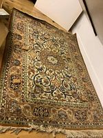 Full view of the rectangular decorative area rug laid out on a wood floor showing detailed patterns and border design.
