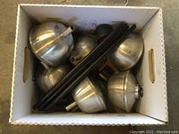 Box containing six silver metal tiki torch heads and six black metal stands.