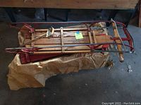 Flexible Flyer wooden sled with metal frame, red and natural finish, lying on brown paper.