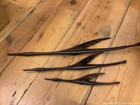 Set of three wooden bird sculptures on pine floor, showing size difference and carved wing details.