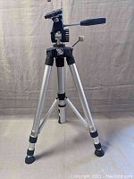 Full view of Bell & Howell tripod showing aluminum legs and black pan-tilt head with adjustable handles.
