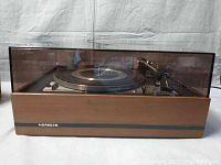 Closed view of Dual 1216 turntable in wood case with tinted dust cover showing front side with NORDREC logo.