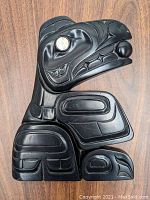 Top view of the black stone relief carving plaque showing the entire figure with carved details and a lighter inlay in the eye.