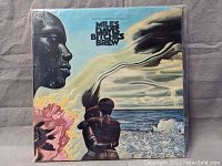 Front album cover of Miles Davis Bitches Brew double album with two figures and ocean background