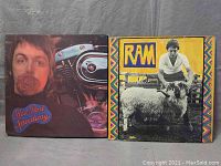 Front covers of two vinyl albums: 'Red Rose Speedway' with Paul McCartney holding a rose and a motorcycle engine visible, next to 'RAM' featuring Paul McCartney with a ram.