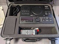 Overview of SuperScope PSD 340 music practice system inside foam-lined hard case, showing main unit, remote control, and power cable.