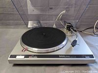 Front-angled view of turntable with platter, tonearm and dust cover open