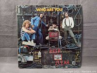 Front cover of 'Who Are You' vinyl album featuring the band members posing with cables and industrial backdrop.
