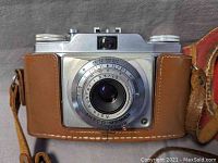 Front view of the Ansco film camera with leather case showing lens and shutter dial details.