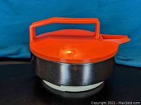 Front view of the kettle showing the stainless steel body, orange lid and handle, and white base.