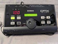 Front view of black Yamaha DTX500 drum trigger module powered on with screen showing kit settings, volume set at 100.