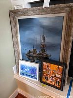 Three framed paintings displayed together against a wall