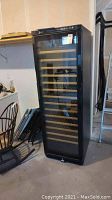 Front view of black Avanti wine fridge with glass door and wooden shelves