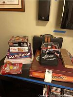 Photo showing stack of board games, puzzles, Dominoes set, and poker chips on table